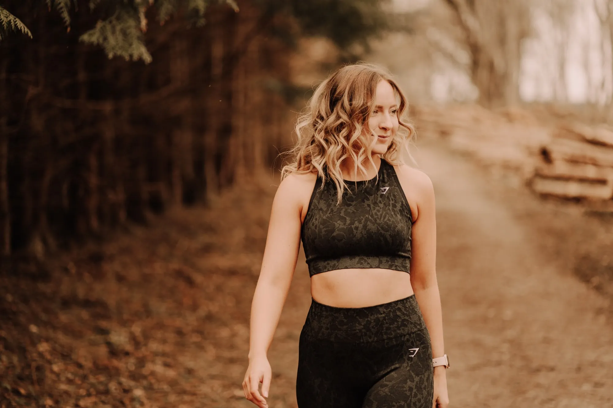 Claire smiling as she walks along a woodland path