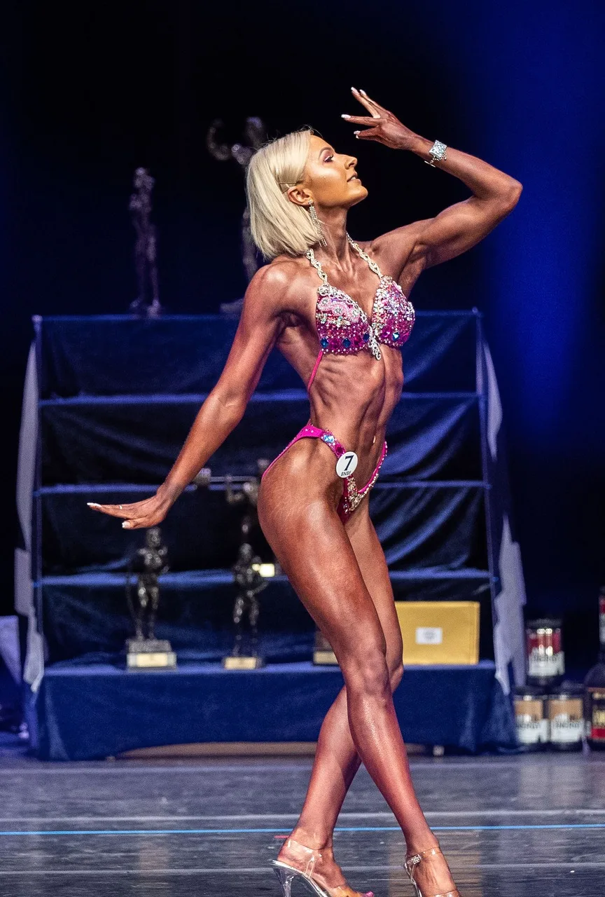 Claire posing on stage at a bodybuilding competition