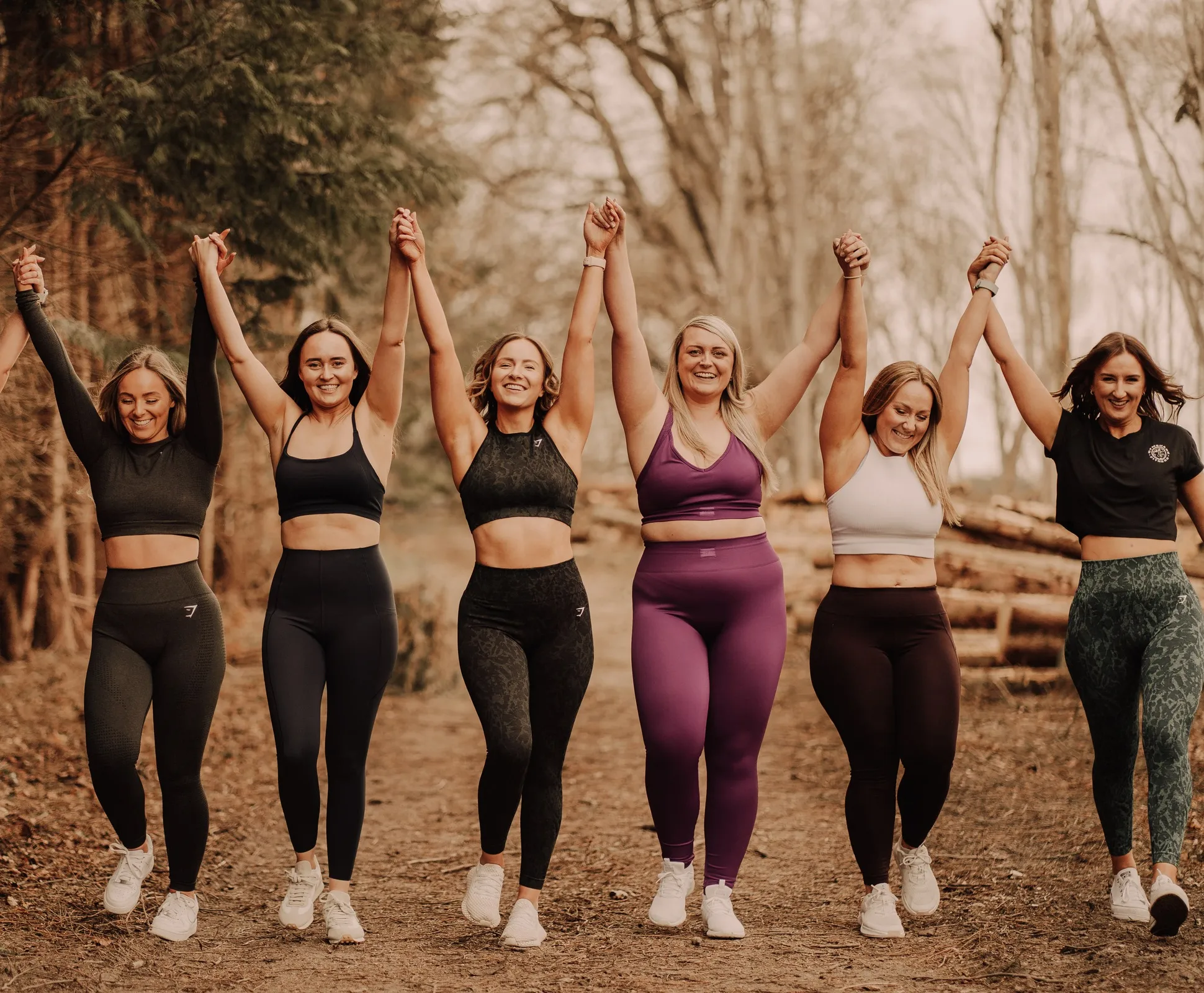 A group of Habit Base women in matching gym kit cheering with their arms in the air